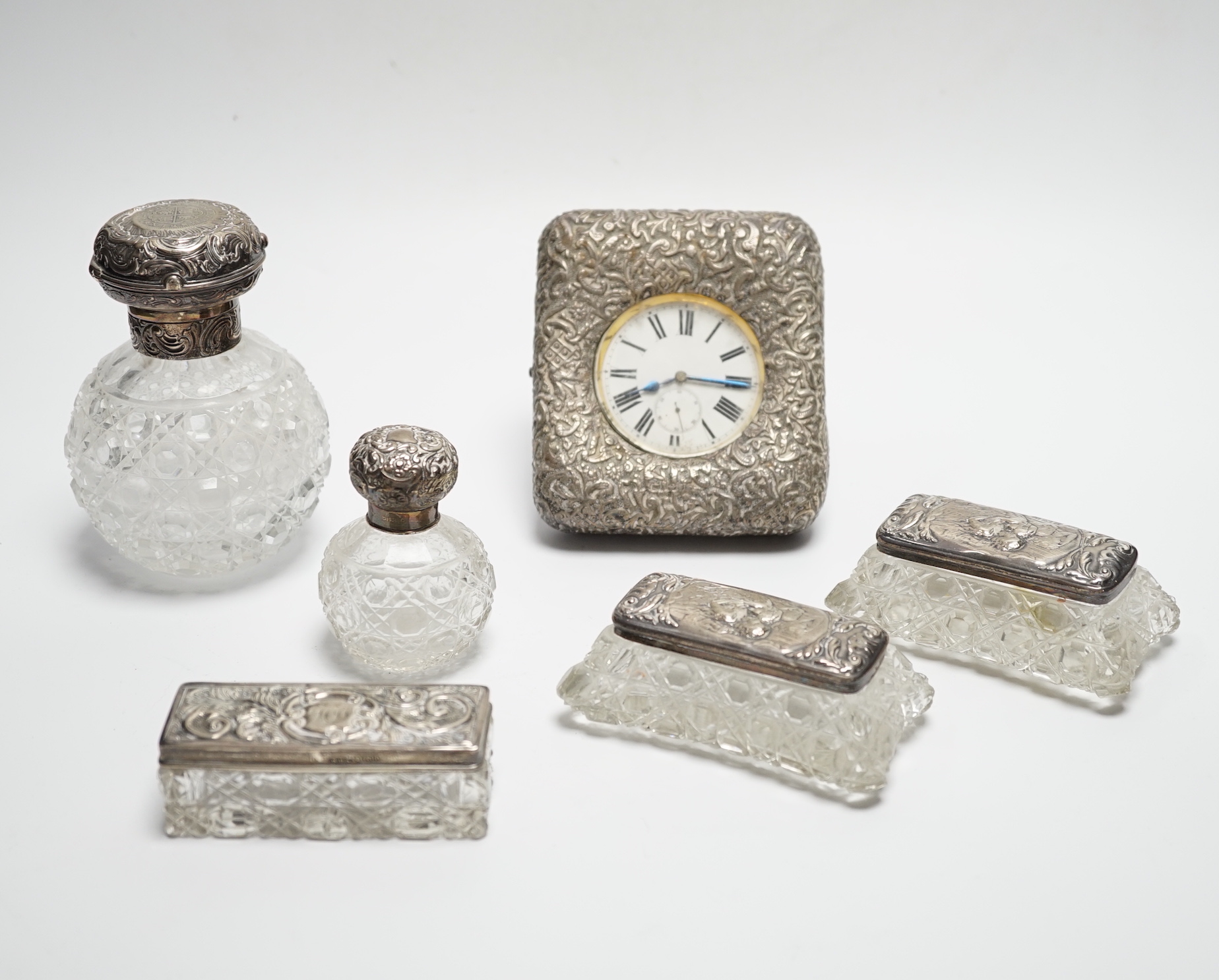 A late Victorian repousse silver mounted travelling pocket watch case, Birmingham, 1898, 11.6cm, with nickel cased pocket watch, together with five silver topped glass toilet jars.